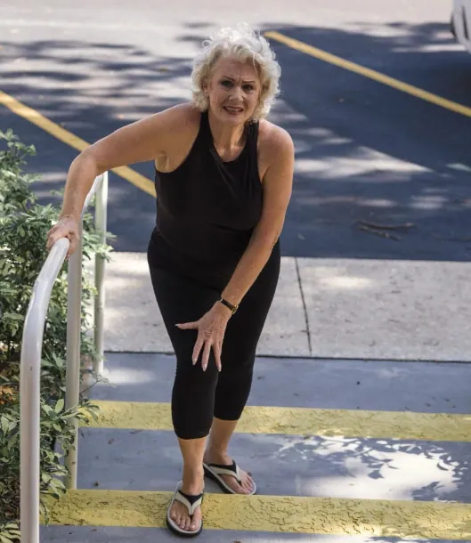 A woman climbing outdoor stairs while holding a rail