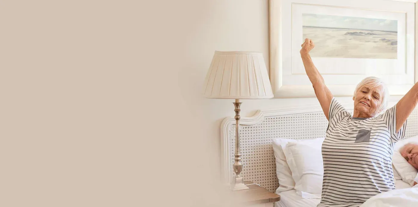 Woman stretching awake in bed in soft morning light