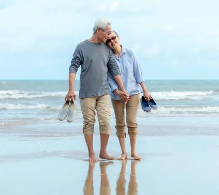 Older couple walking barefoot along a beach