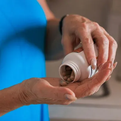 A hand tipping capsules out of a supplement bottle