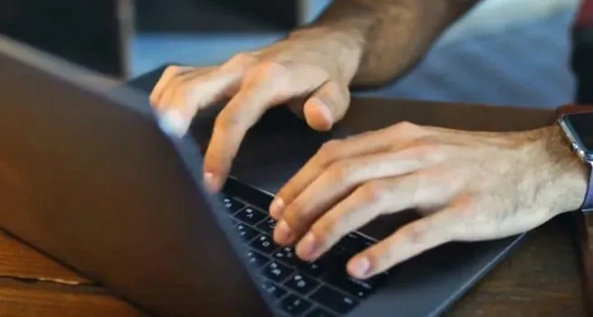 Hands typing on a laptop keyboard
