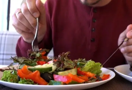A man eating a green salad at a table