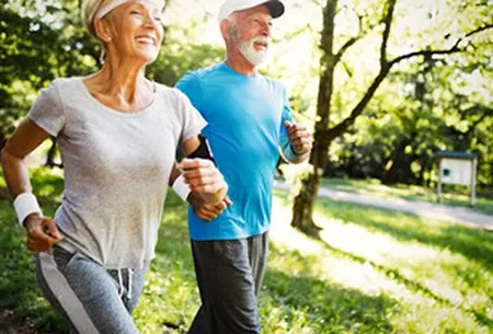 Older couple jogging together along a park path