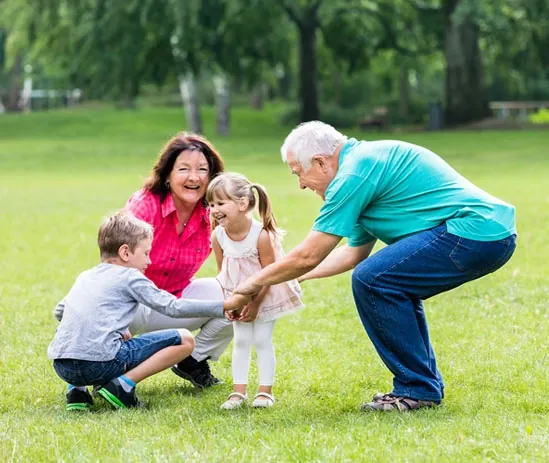 Grandparents playing with children on the grass