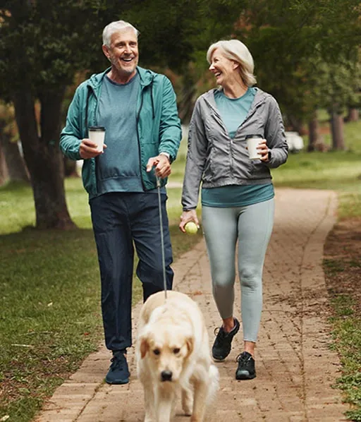 Couple walking a dog on a sunny path