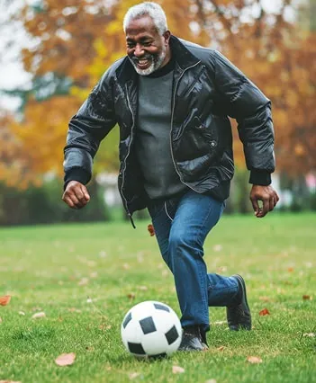 Older man kicking a soccer ball in a park